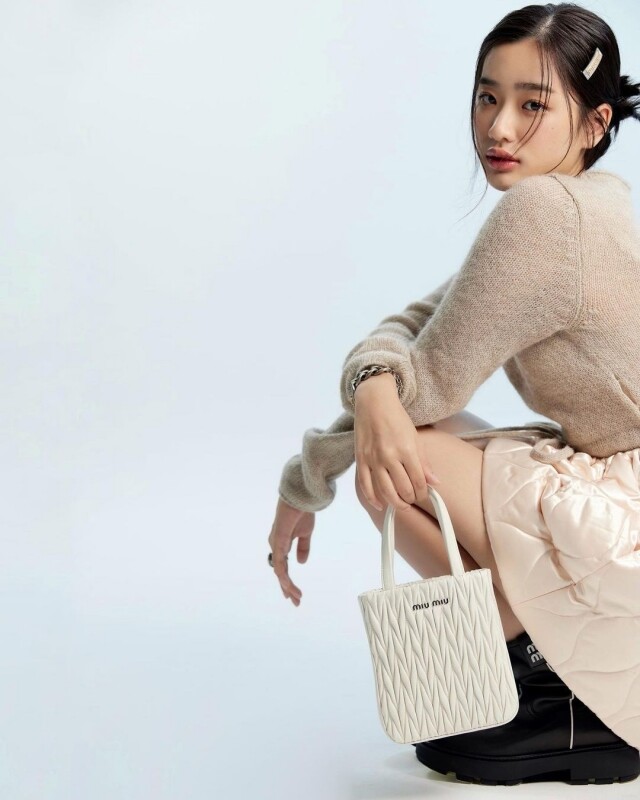 時尚品牌 Miu Miu 一向深受少女喜愛，由正值青春的 Tu 演繹品牌風格再合適不過。Tu 穿上淺卡其的毛衣搭配淺粉色短裙，顯得優雅、甜美，而手上提著 Matelasse 手袋為造型錦上添花。
