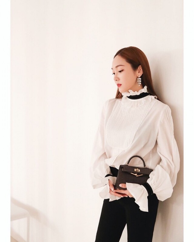 黑色的 Hermes Mini Kelly 手袋，Jessica 著用率甚高，襯上白色的絲質恤衫，高貴大方。