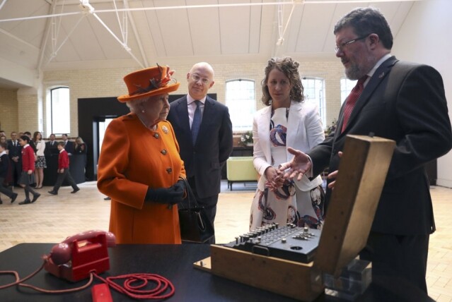 英女皇在科學館內參觀了一個展覽，其間職員向她解釋展品的資訊。