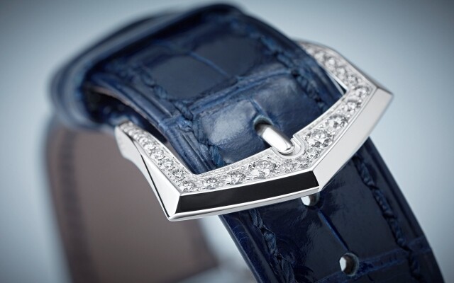 手工縫製的藍色方形鱗紋鯉魚皮錶帶，延續瞭柔美優雅的風格，搭配鑲鑽針扣。 