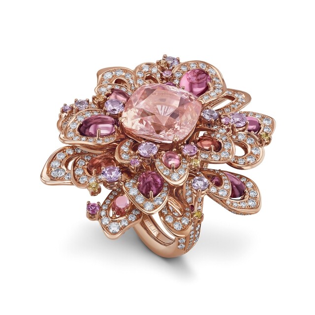 最近，Gübelin 帶來全新的 Aurora 珠寶系列，特別以來自斯里蘭卡，珍貴橙粉紅色帕帕拉恰藍寶石的結構為靈感，設計出 Rising Lotus 及 Splendid Feather珠寶。橙粉紅的藍寶石非常珍罕，有人曾形容橙粉紅的藍寶石色澤有如蓮花盛開的色彩，所以這枚 Rising Lotus 以晨曦中的蓮花為設計概念，主石是一顆 14 卡的帕帕拉恰藍寶石，三層鑲有寶石葉片，一共鑲嵌 14 顆蛋面粉彩色藍寶石及超過 550 顆明亮切割圓鑽，營造出漸變的效果有如露珠沾於花瓣之上，立體且栩栩如生。