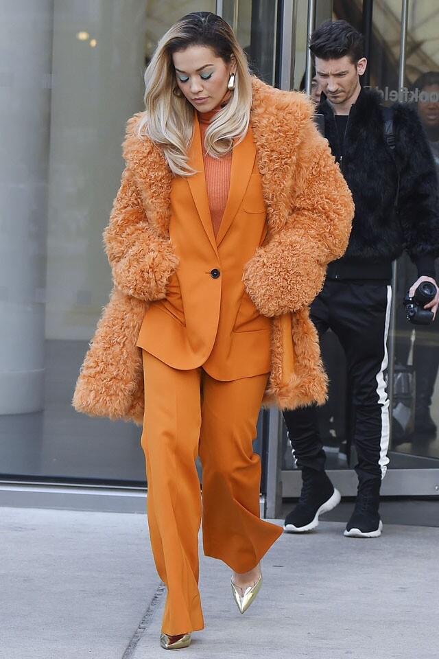 Rita Ora 以橙色西裝佩上同色系的樽領冷衫和毛毛大衣