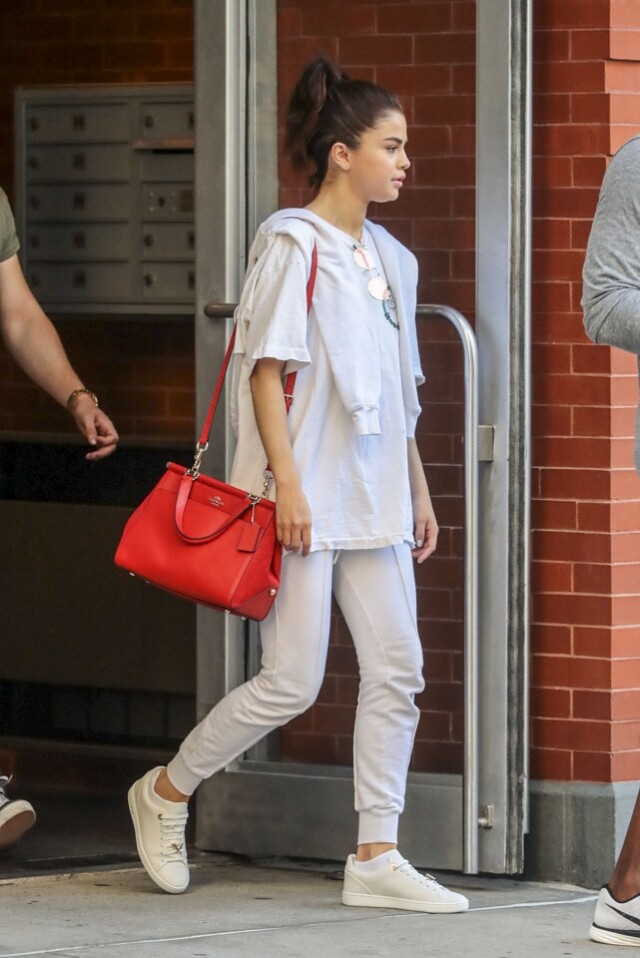 穿著一身全白運動裝的 Selena Gomez 配上鮮紅 Coach手袋。