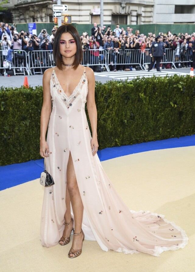 Selena Gomez 穿著碎花開衩長裙，手拎相同花色的迷你鏈條 clutch bag。