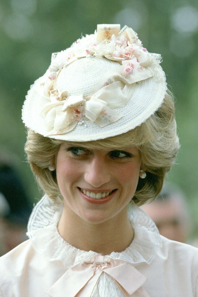 1983 年戴安娜王妃以蝴蝶網織帽配搭古董服飾出席探訪活動。