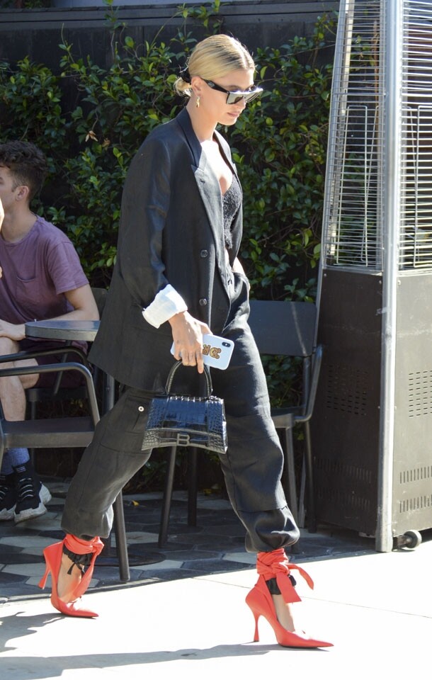 Hailey Bieber 一身黑色造型，令目光立刻落於她腳上橙紅色綁帶尖頭鞋。