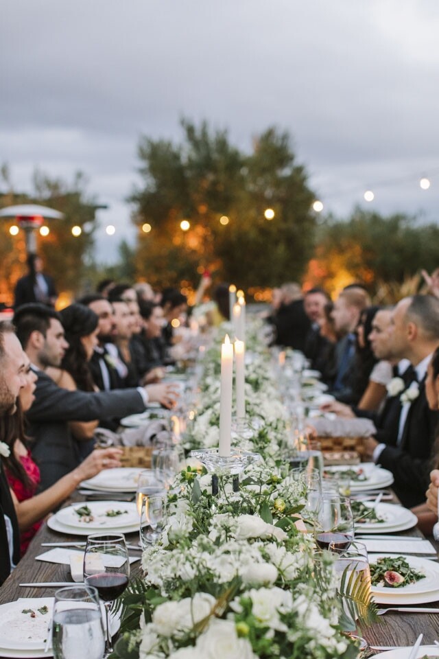 主餐桌上擺放有以白色花卉為主的綠色植物。