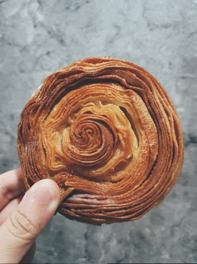 Kouign-amann 是一種層次豐富的圓形酥脆糕點,以麵糰包裹糖和牛油重覆折疊製成,造法與千層酥皮類似。 Kouign-amann 是一種層次豐富的圓形酥脆糕點,以麵糰包裹糖和牛油重覆折疊製成,造法與千層酥皮類似。