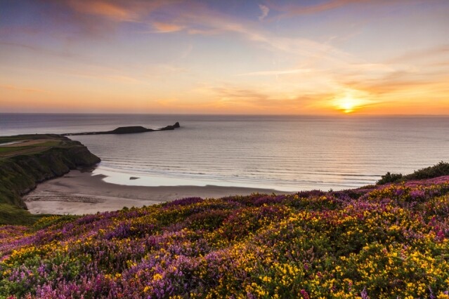 羅西里灣，英國威爾斯 號稱全英國最美的沙灘！英國天氣的或許不適合曬日光浴，但羅西里灣（Rhossili Bay）的日落也許會令你驚喜。春夏季時，海岸旁邊的小山丘還會開花，同時滿足女生的兩個願望！