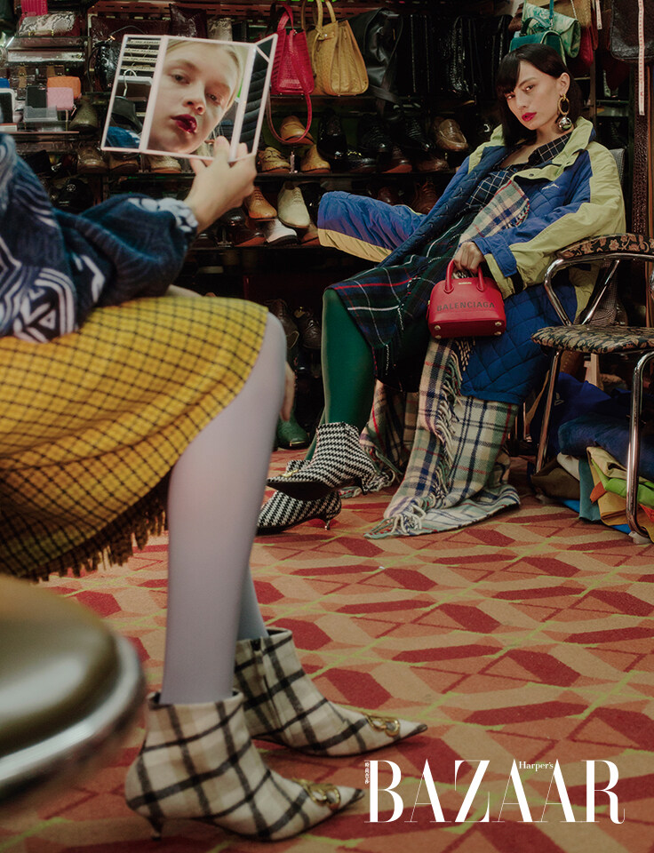 BALENCIAGA圖案外套、格紋高腰裙、格紋短靴。BALENCIAGA格紋恤衫、風衣連格紋絨圍巾、大款金屬耳環、格紋短靴及標誌皮革手挽袋。